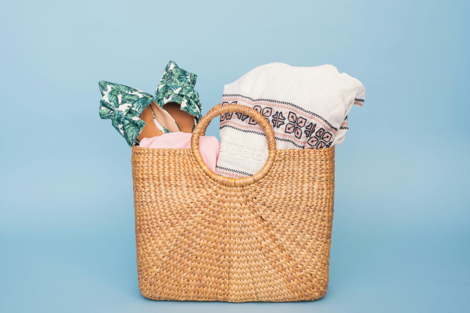 A straw beach tote packed with everything you need for a fun day eat the beach.