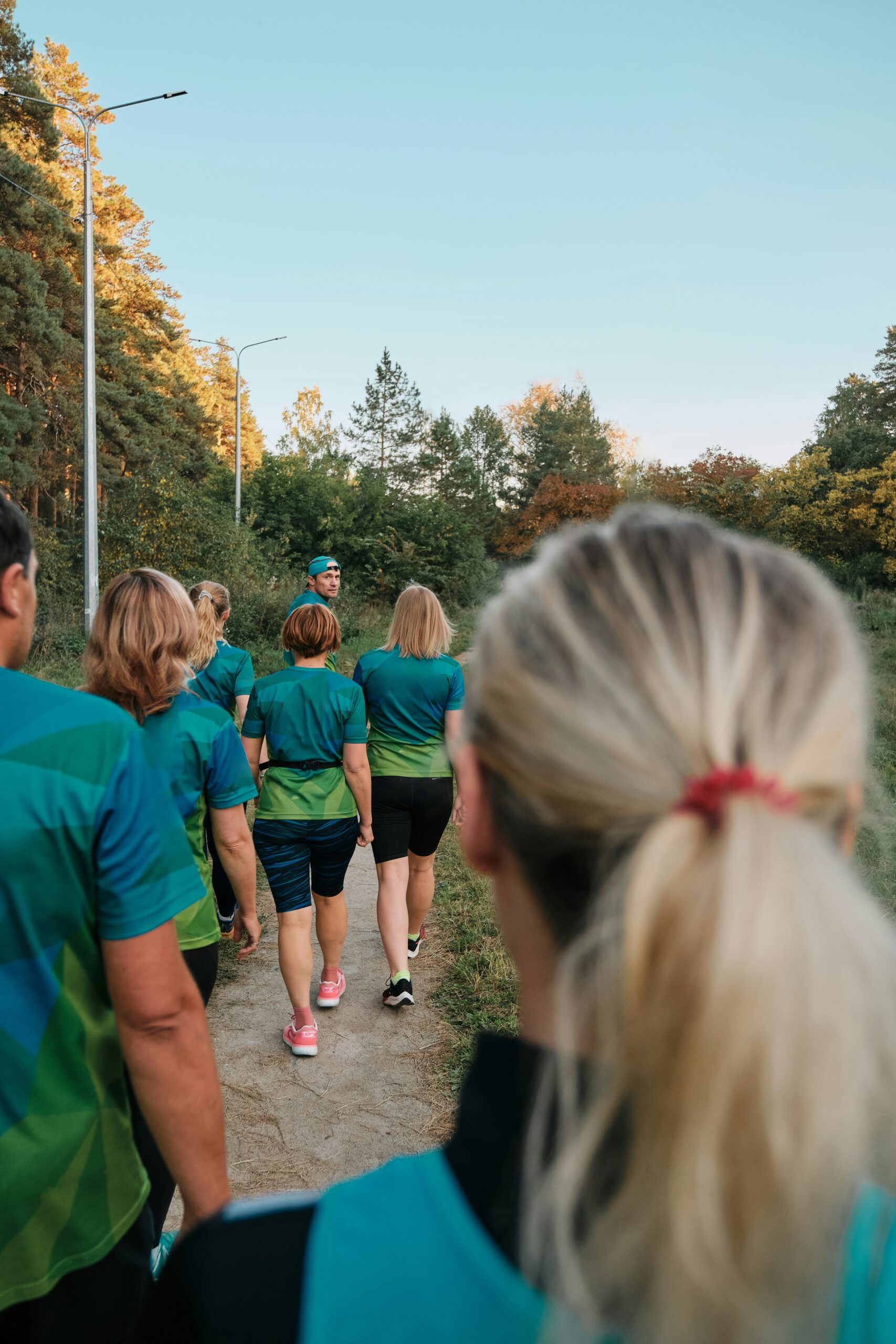 walk-a-thon-participants-coordinated-shirts Group of walk-a-thon participants wearing coordinated teal and green t-shirts walking together on a tree-lined path