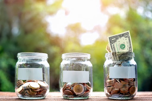 micro-donations-nonprofit-giving-jars Three glass jars filled with coins and a dollar bill, representing small donations adding up