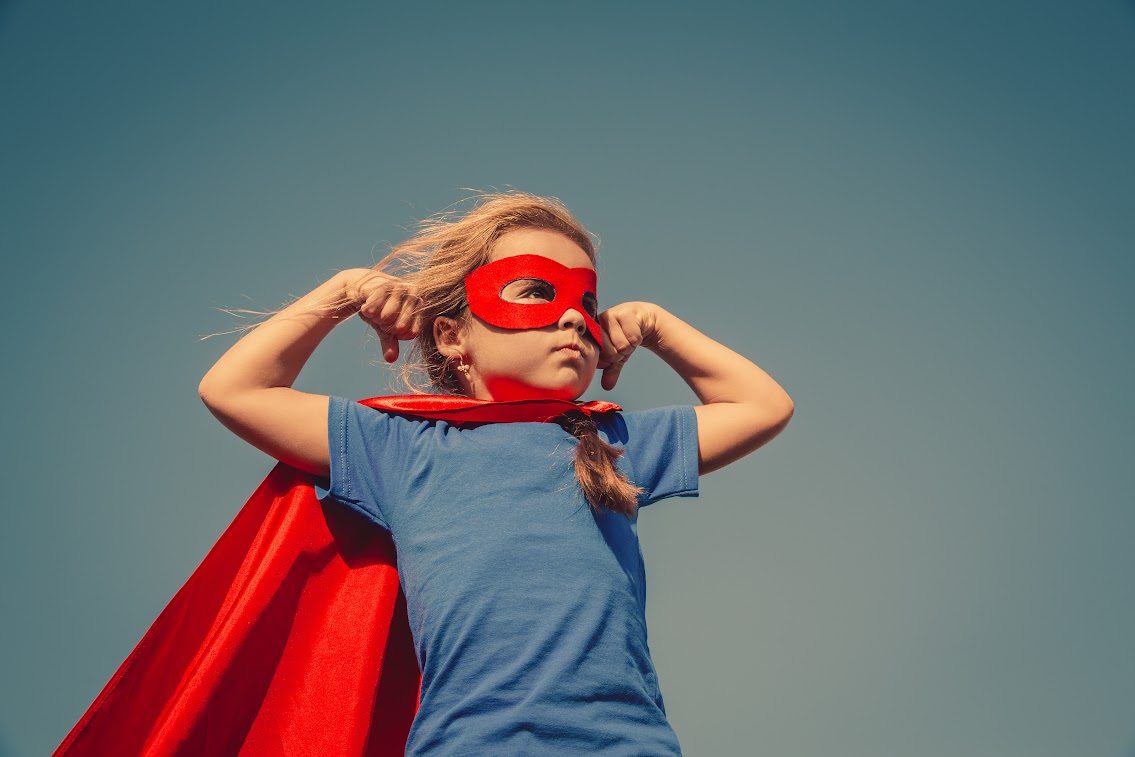 Child in red cape and mask striking a superhero pose, symbolizing the power of small actions for nonprofits