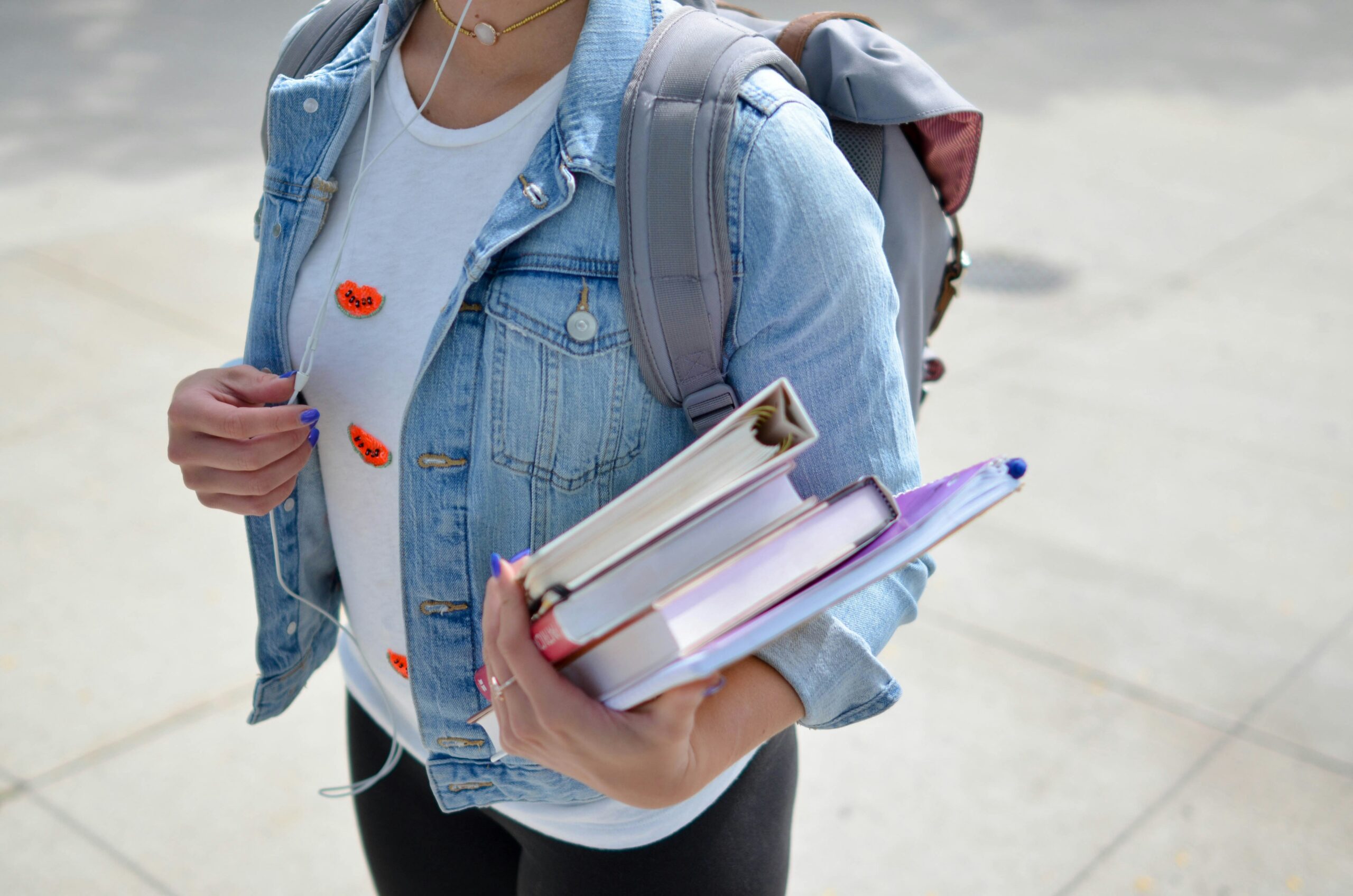 Student carrying textbooks and wearing a backpack, ready for the new school year
