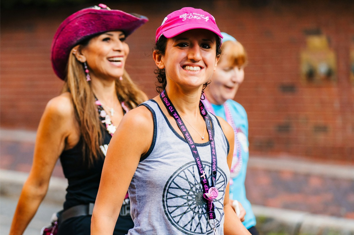 Happy peer-to-peer fundraising participants wearing matching pink event caps and medals, demonstrating event-specific branded merchandise
